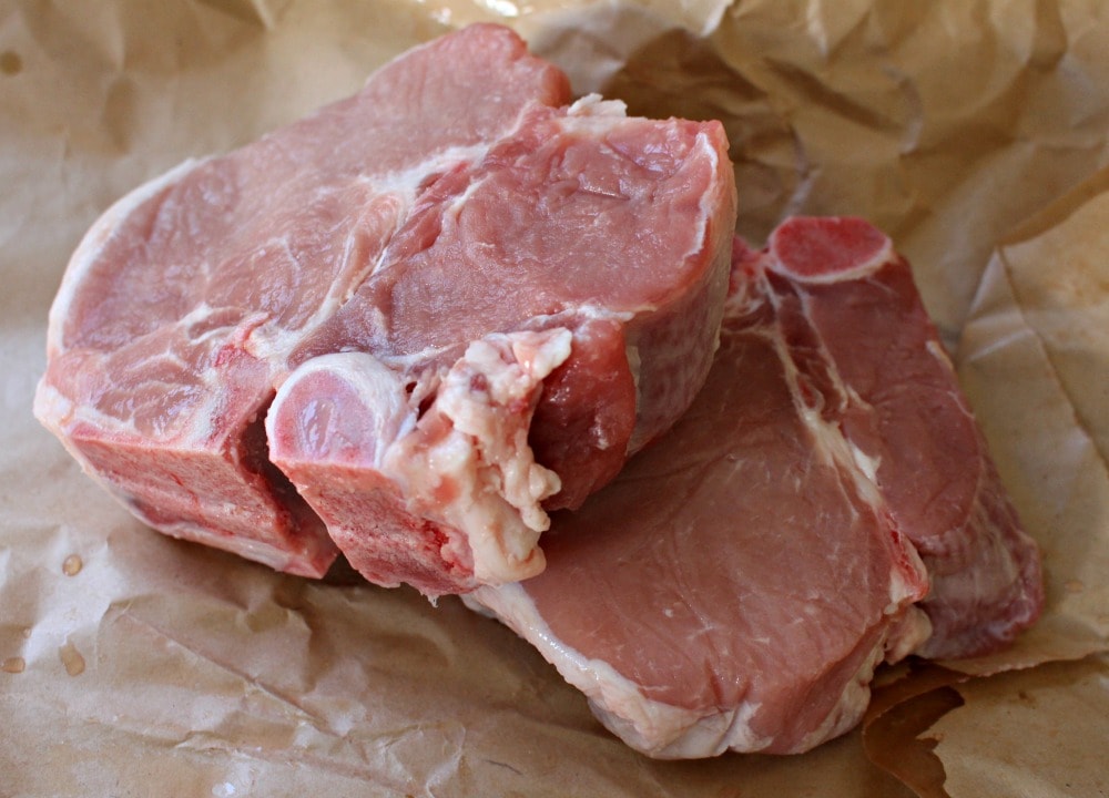 Two, raw and thick pork chops on brown paper. 