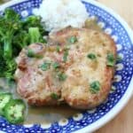 Salsa Verde Pork Chops on a blue plate served next to white rice and green broccoli.