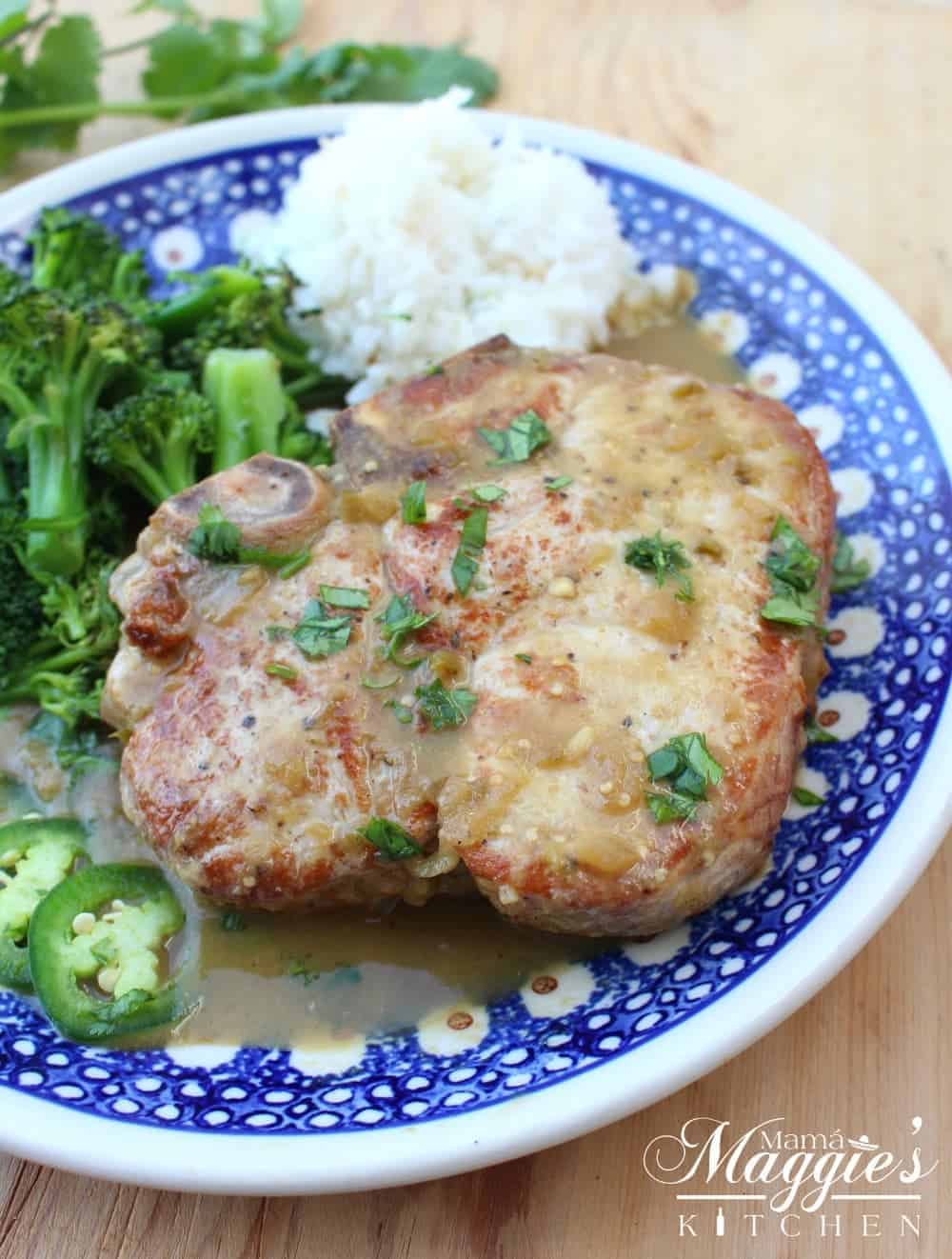 Salsa Verde Pork Chops on a blue plate served next to white rice and green broccoli. 