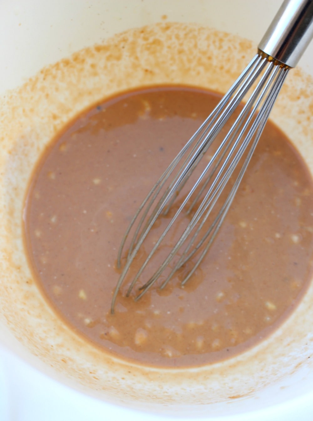 A bowl with the marinating sauce for Pescado Zarandeado and a metal whisk.