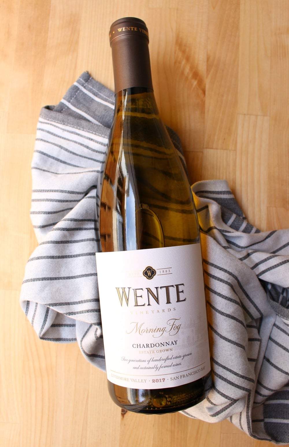 A bottle of Wente Vineyards Morning Fog Chardonnay over a kitchen towel.