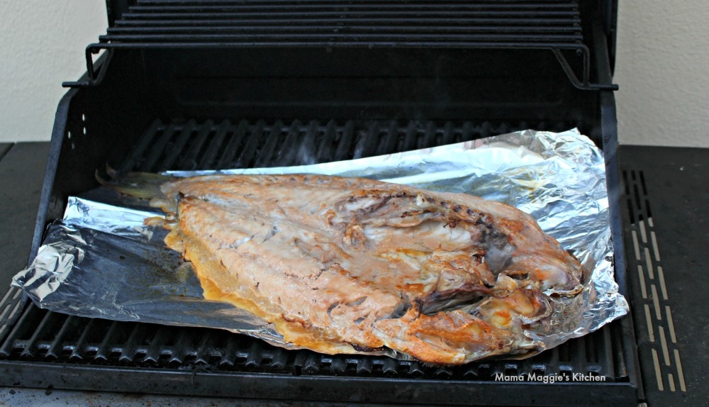 Pescado Zarandeado cooking on top of foil paper on the grill.