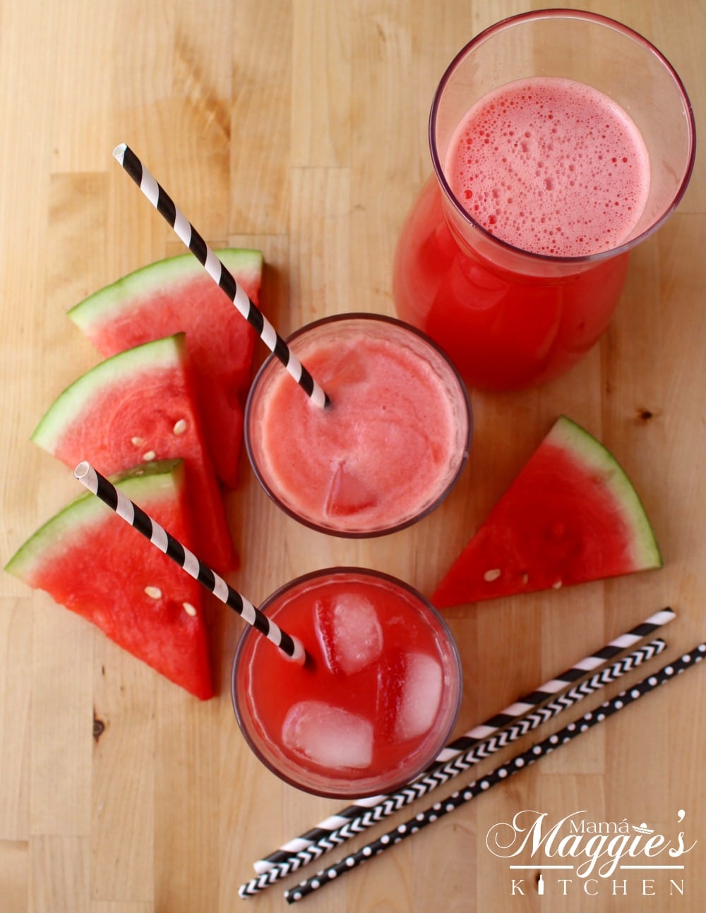 Watermelon agua fresca glasses next to watermelon slices and black and white straws.