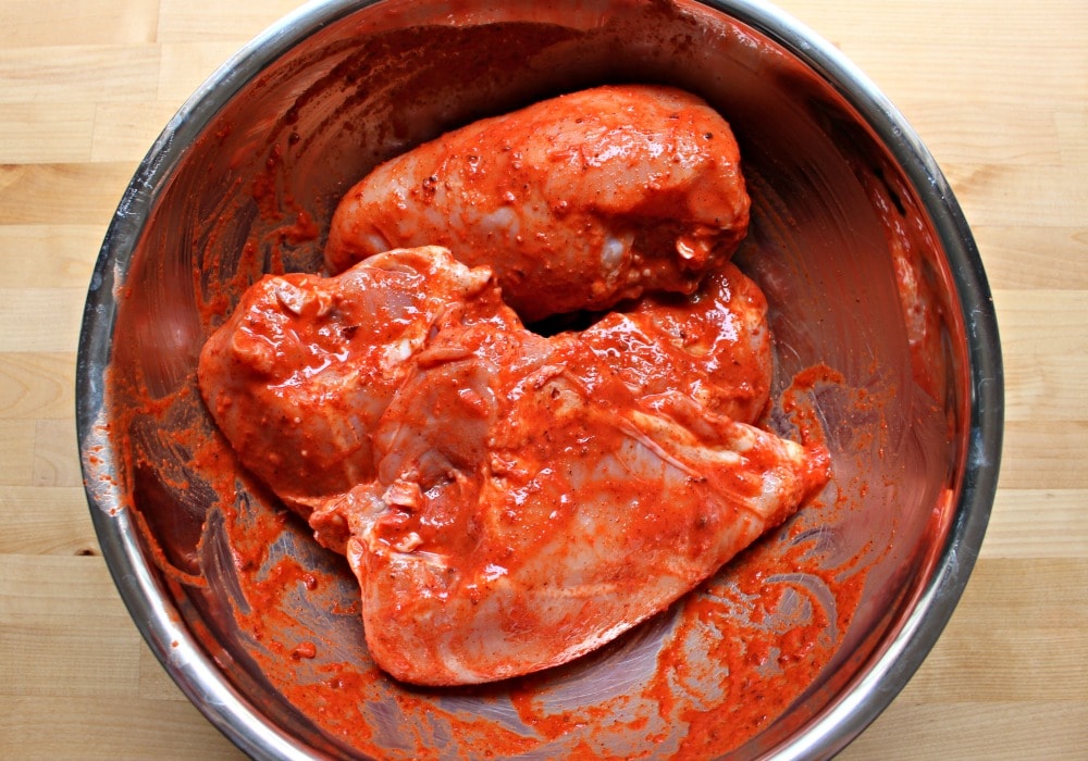 Chicken breast marinated with pibil sauce in a metal bowl. 