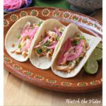Pollo Pibil (Yucatan Style Chicken) tacos on a clay plate topped with Mexican pickled onions.