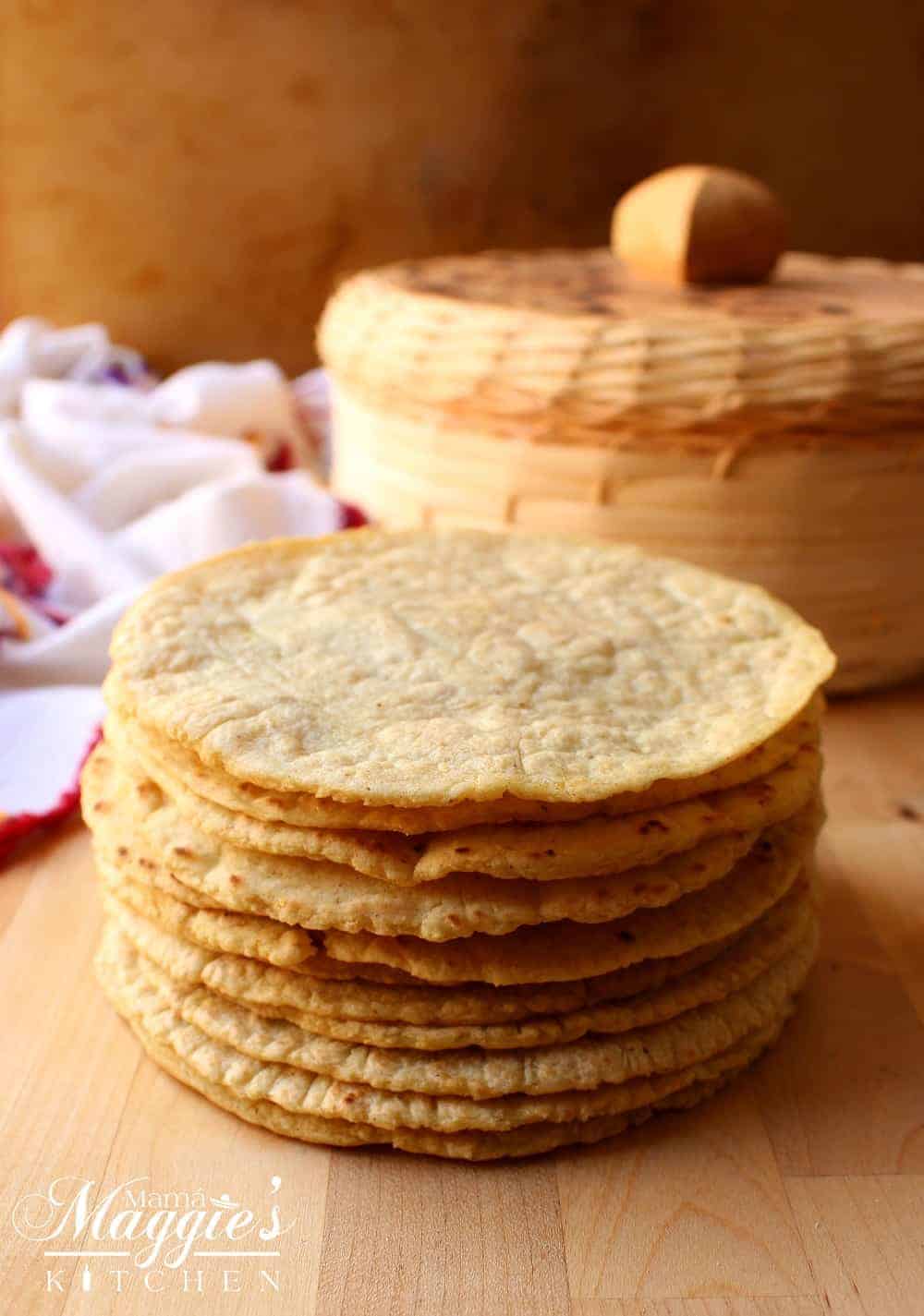 A stack of homemade corn tortillas in front of a tortilla holder. 