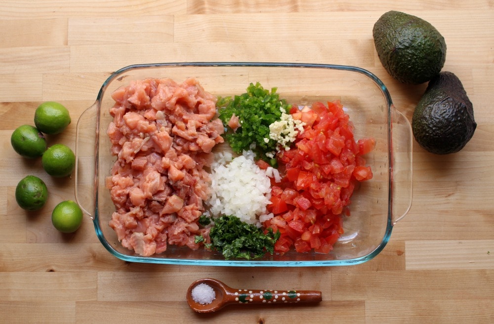 All the ingredients for Salmon Ceviche in a large glass container. 