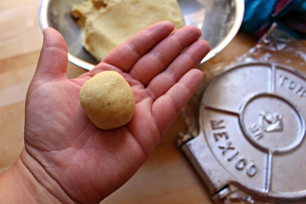 Hand holding a ball of corn dough.
