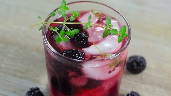 Blackberry Smash Margarita in a glass topped with green thyme.