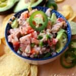 Salmon Ceviche in a bowl topped with a jalapeno slice and surrounded by tortilla chips.