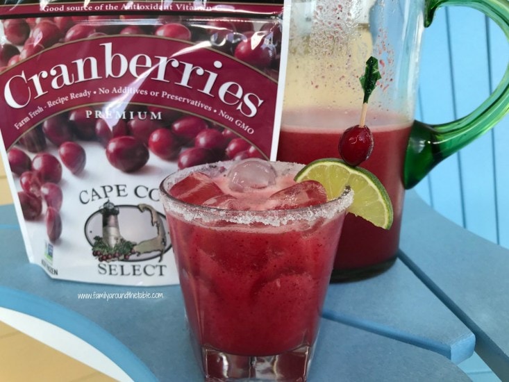 Cranberry Lime Margarita served with a wedge of lime and next to cranberries.
