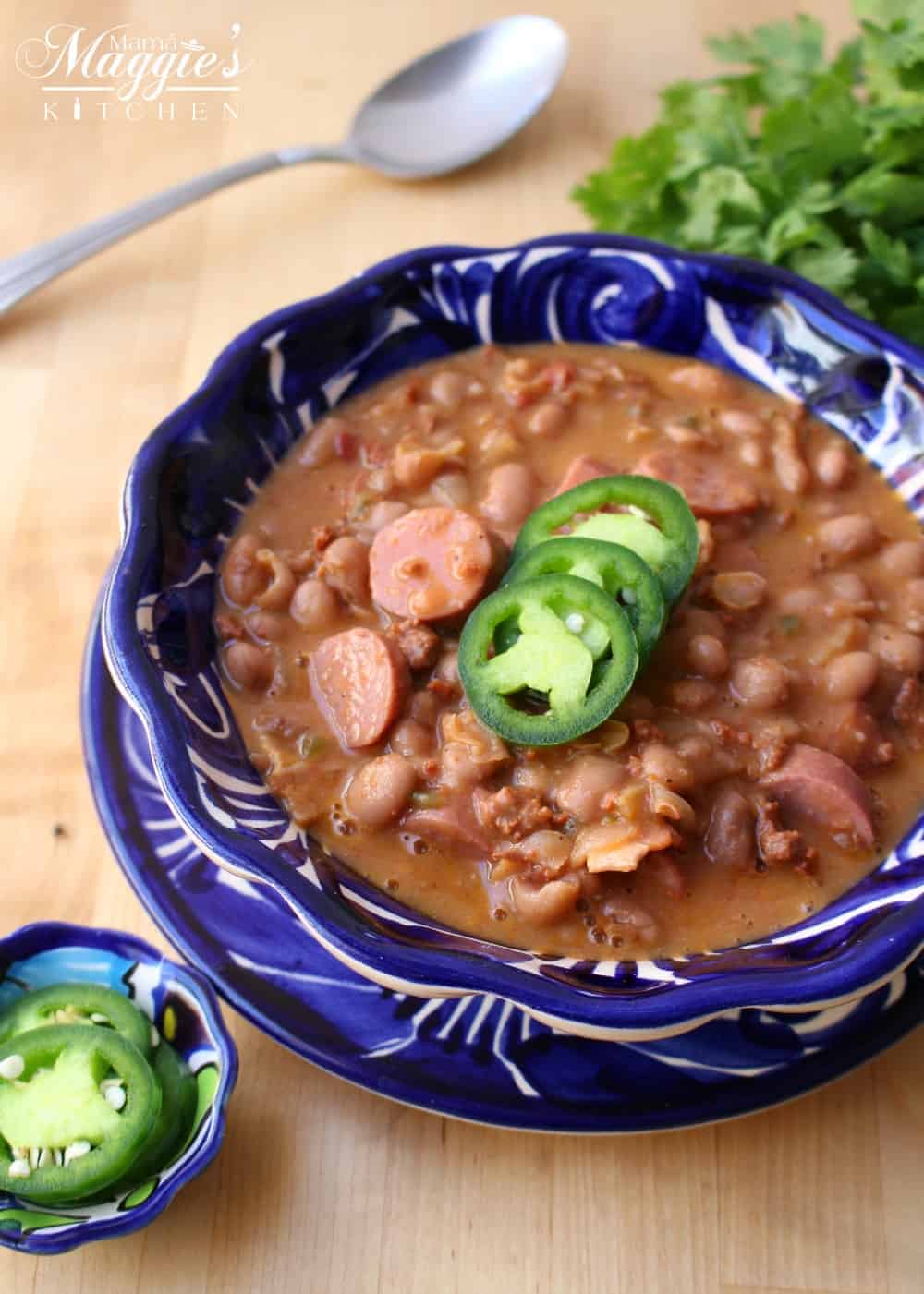 Charro Beans in a decorative blue bowl topped with jalapeno slices.