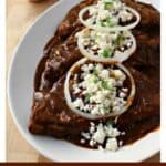Sweet Enchiladas on a white plate topped with onion slices and queso fresco.
