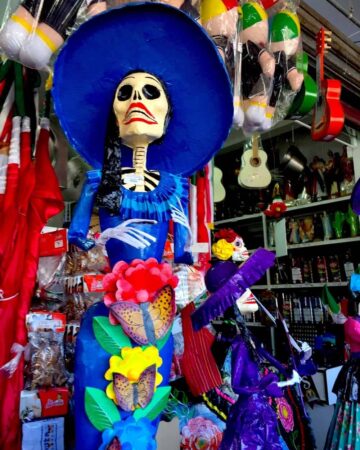 A stature of La Catrina wearing a blue hat and a blue dress.