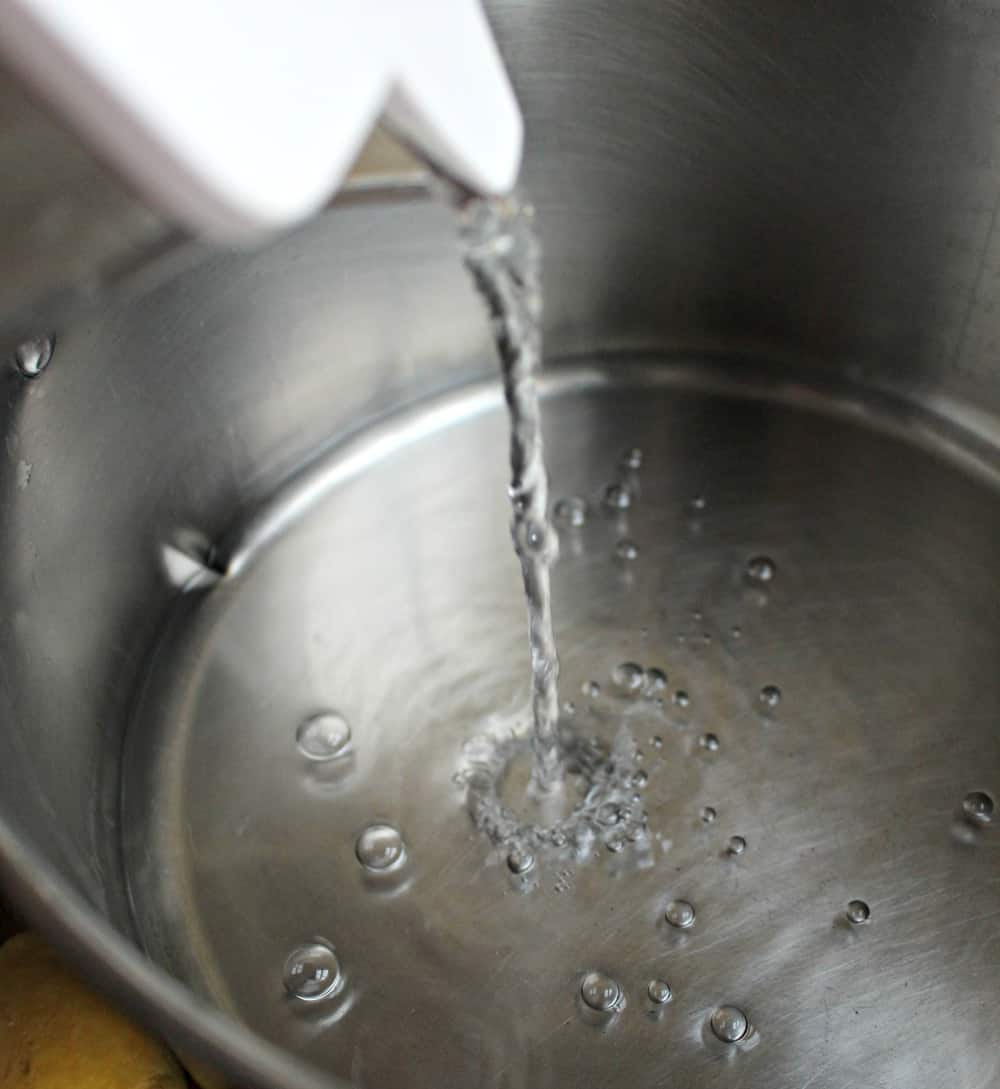 Water pouring into a metal stock pot. 