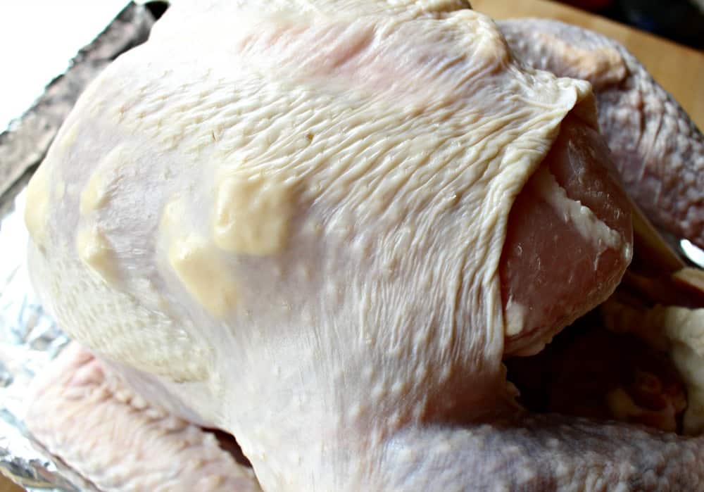 A raw turkey with tabs of butter under the skin. 