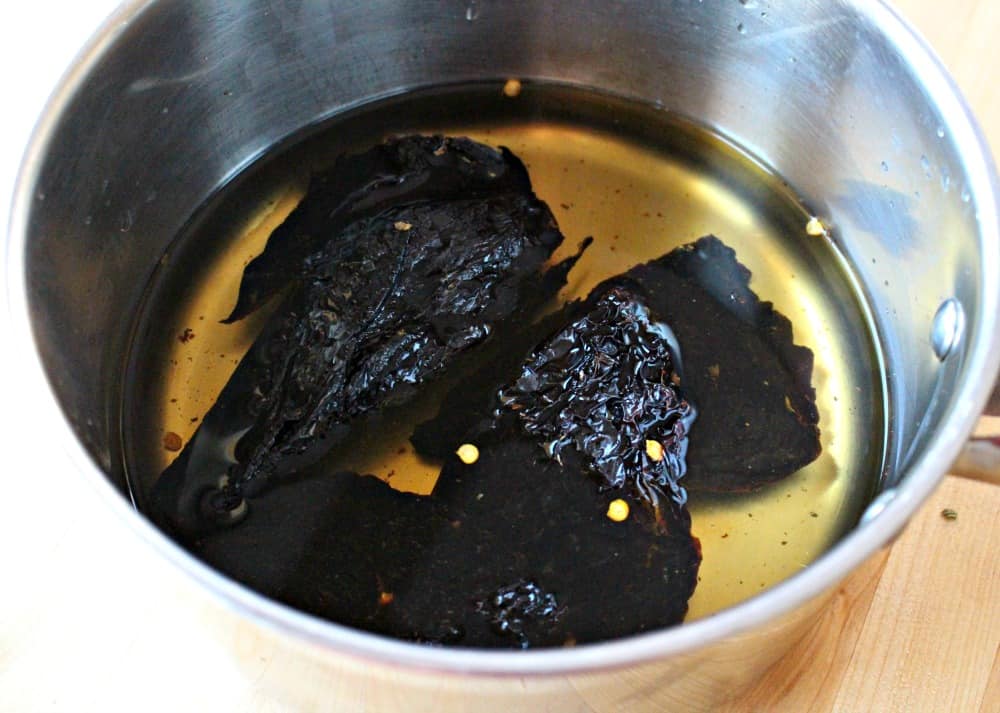 Rehydrates ancho chiles in a pot with water.