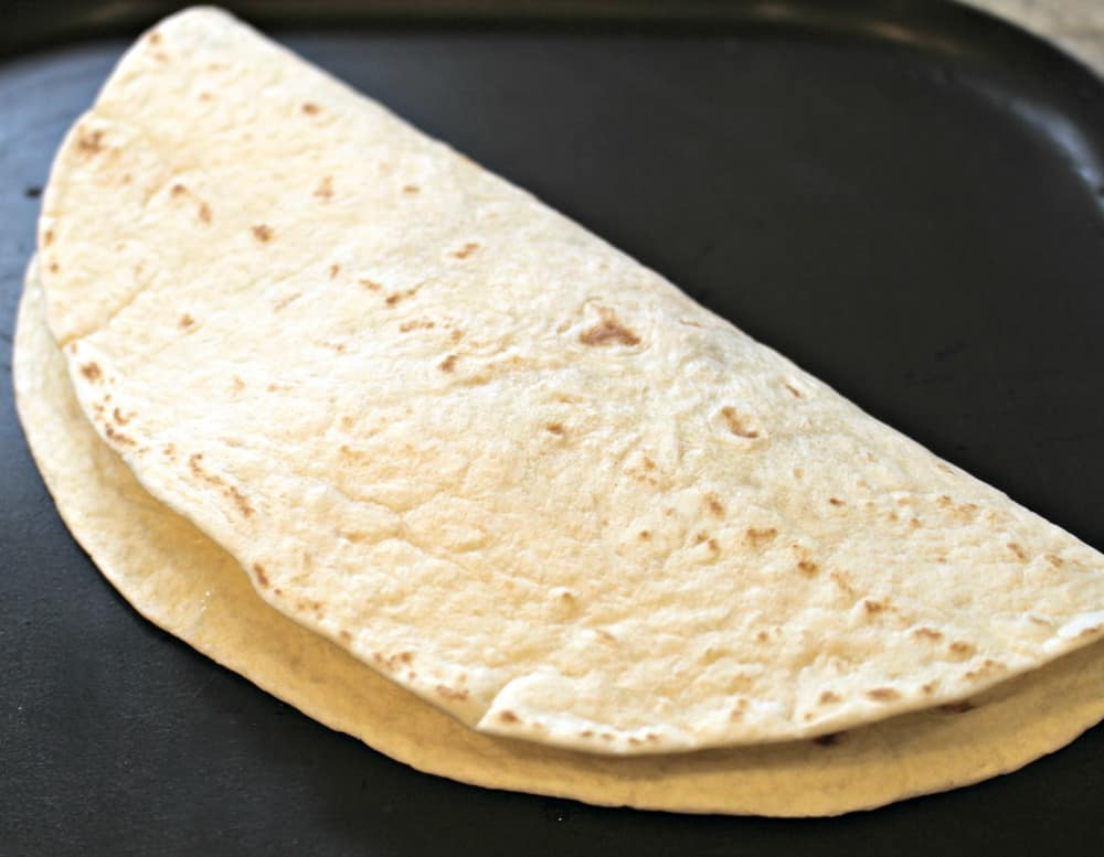 A quesadillas cooking on a griddle. 