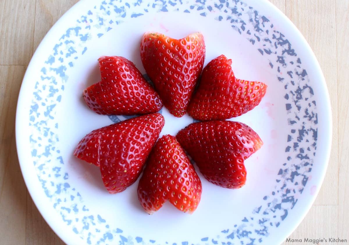 A circle of heart-shaped strawberries on a plate.