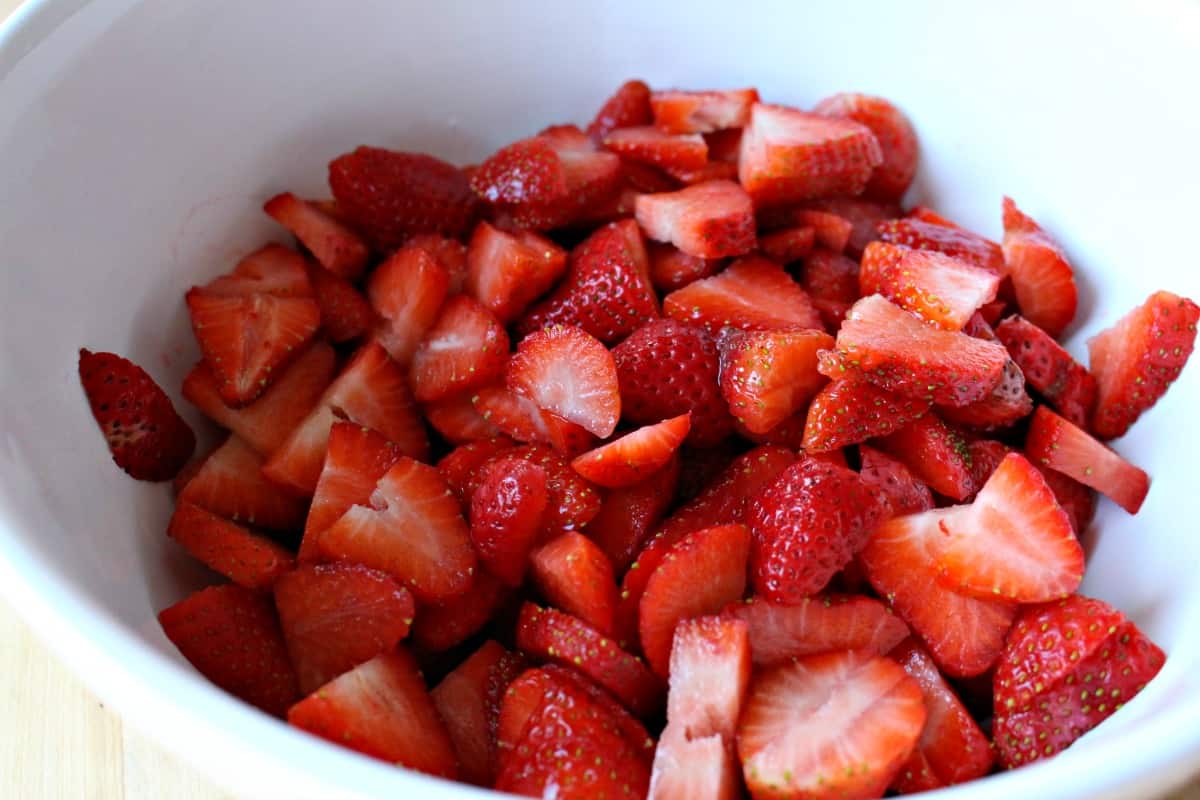 Sliced strawberries in a white bowl.