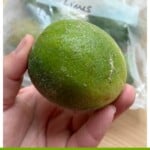 A hand holding a frozen lime.