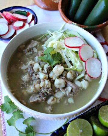 Instant Pot Pork Pozole Verde in a white bowl topped with cilantro, radishes, and cabbage.