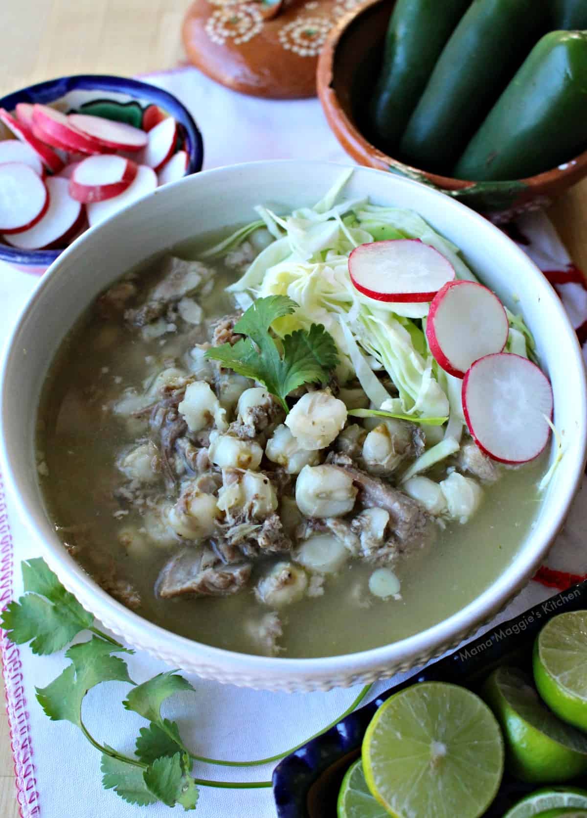 Instant Pot Pork Pozole Verde in a white bowl topped with cilantro, radishes, and cabbage. 