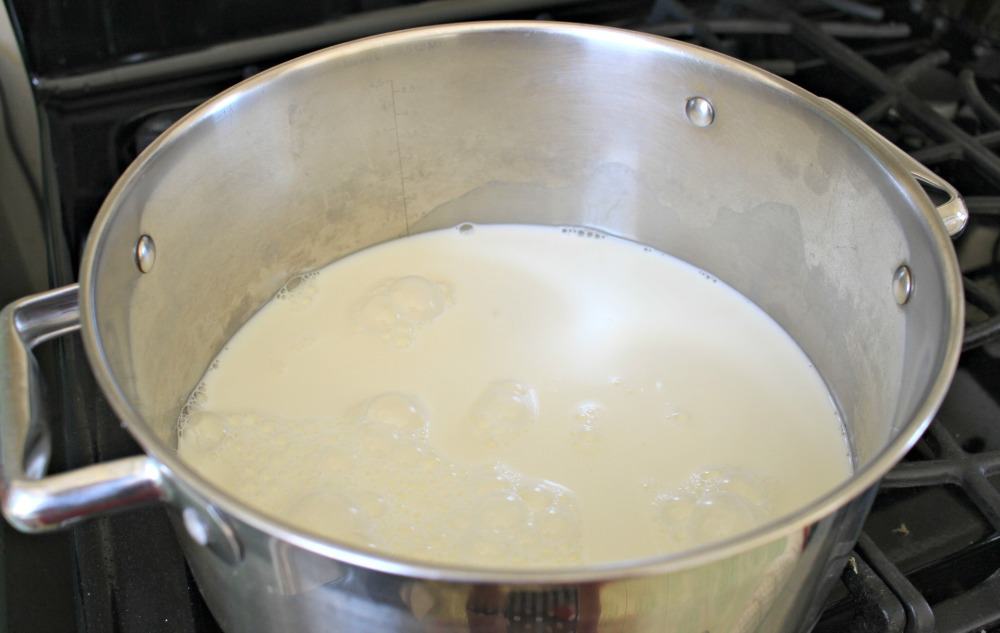 A stock pot with milk inside on a stove. 
