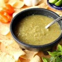 Tomatillo Habanero Salsa in a black bowl surrounded by chips.
