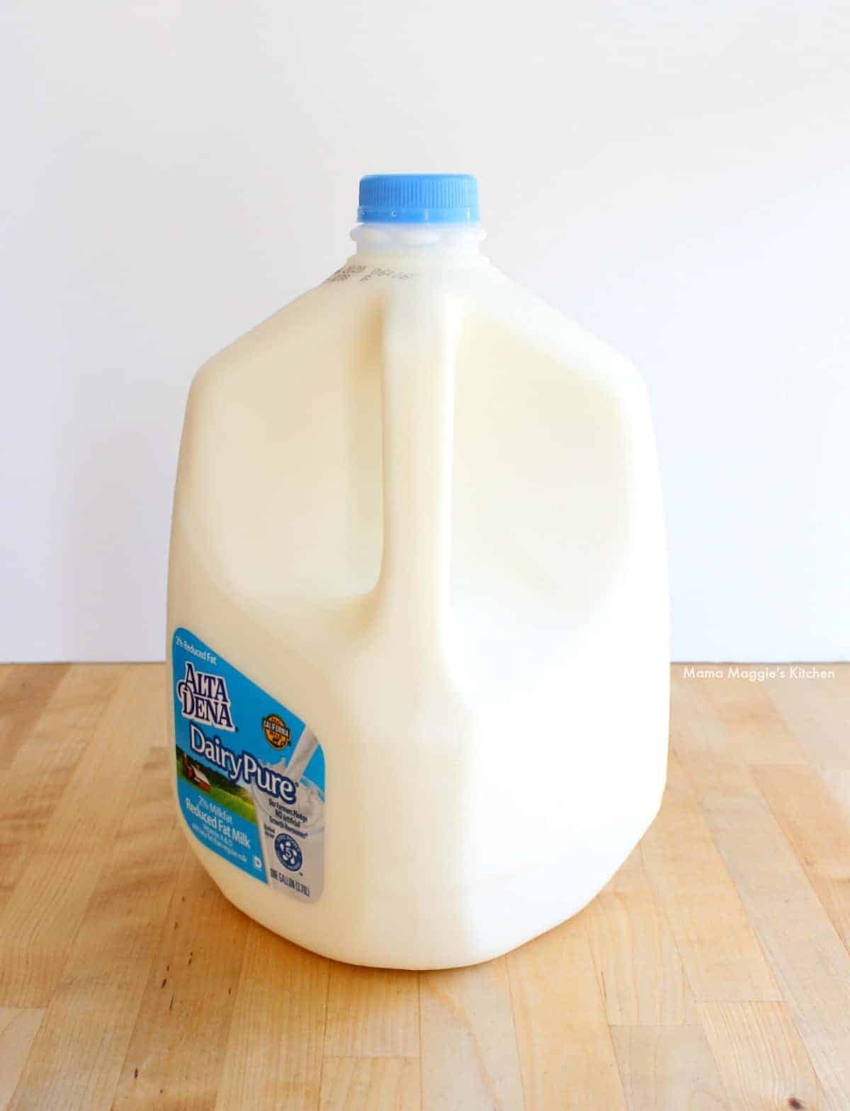 A gallon of milk on a wooden table.
