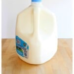 A gallon of milk on a wooden surface.