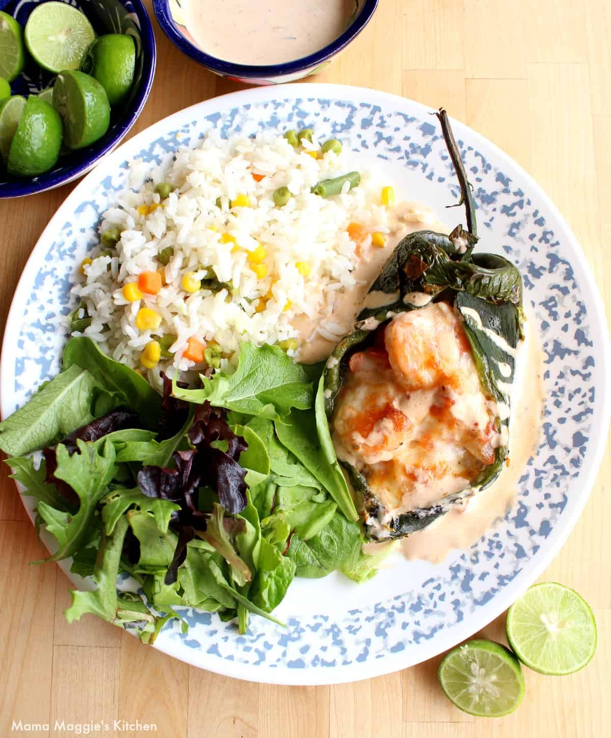 Shrimp Chile Relleno served on a plate next to a salad and rice.