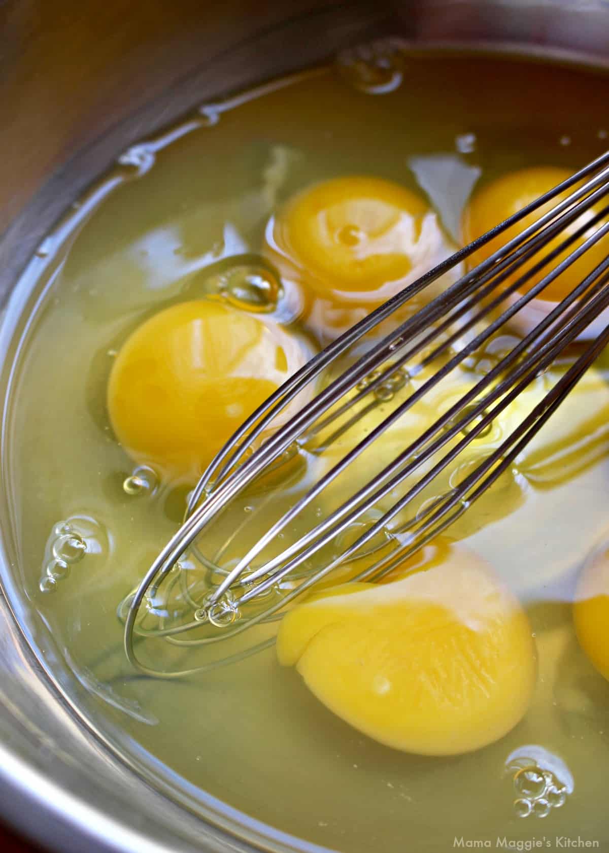 A whisk beating eggs in a bowl.