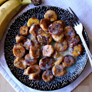 Mexican fried bananas served on a blue plate with a fork.
