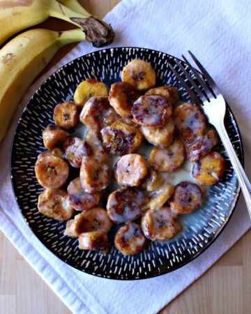 Mexican fried bananas served on a blue plate with a fork.