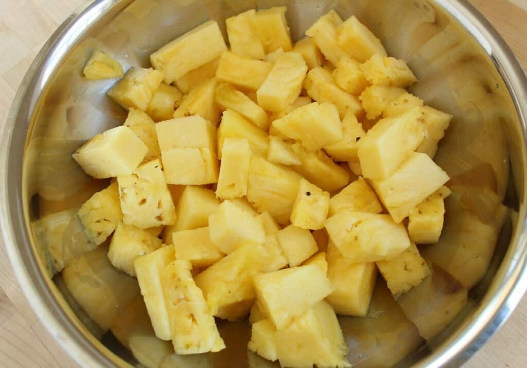 A metal bowl with freshly diced pineapple.