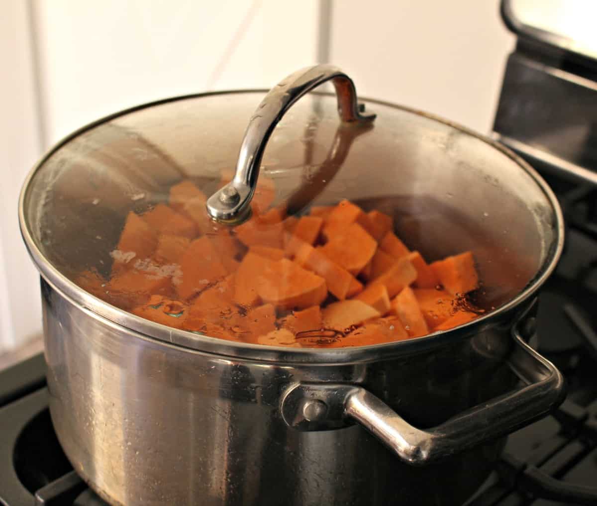 A pot cooking on the stove filled with sweet potatoes.