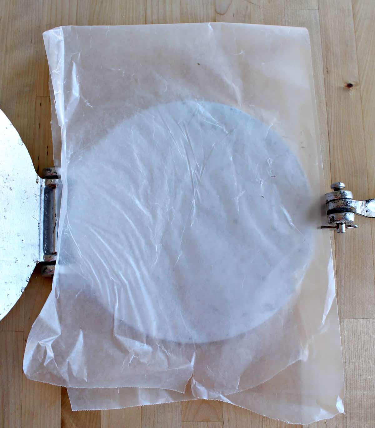 Wax paper placed inside of a tortilla press.