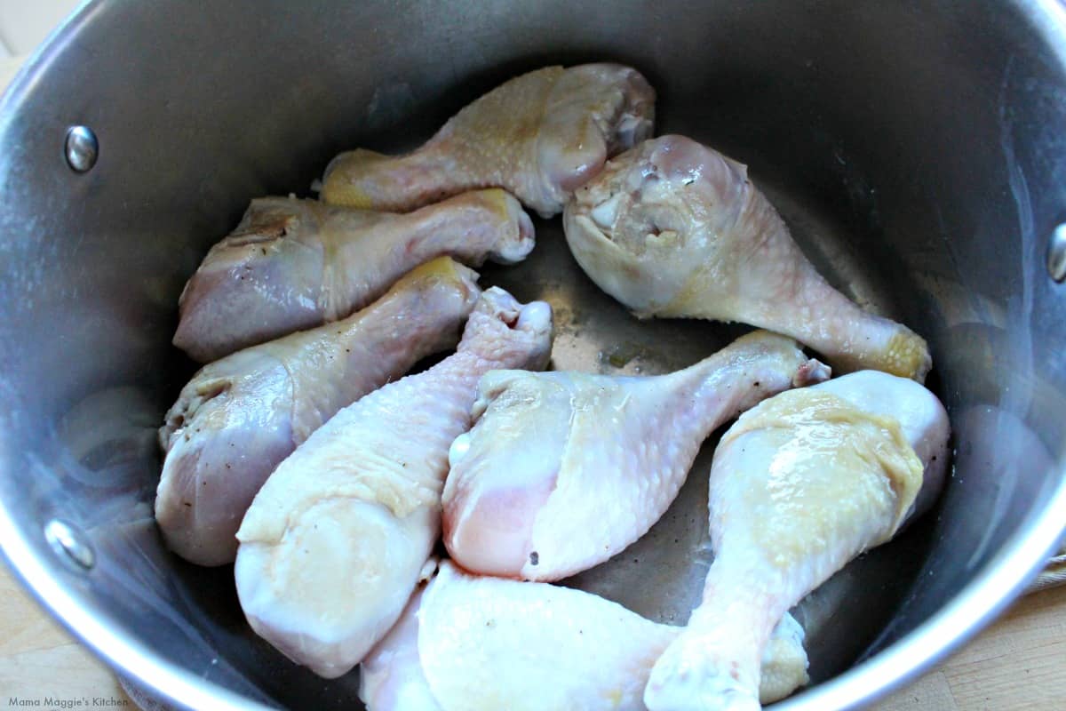 Chicken legs searing in a large stock pot.