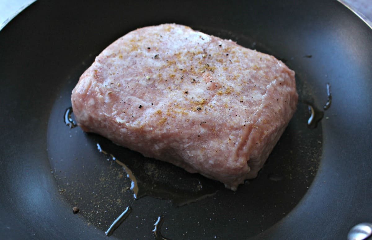 Raw ground pork cooking in a skillet.