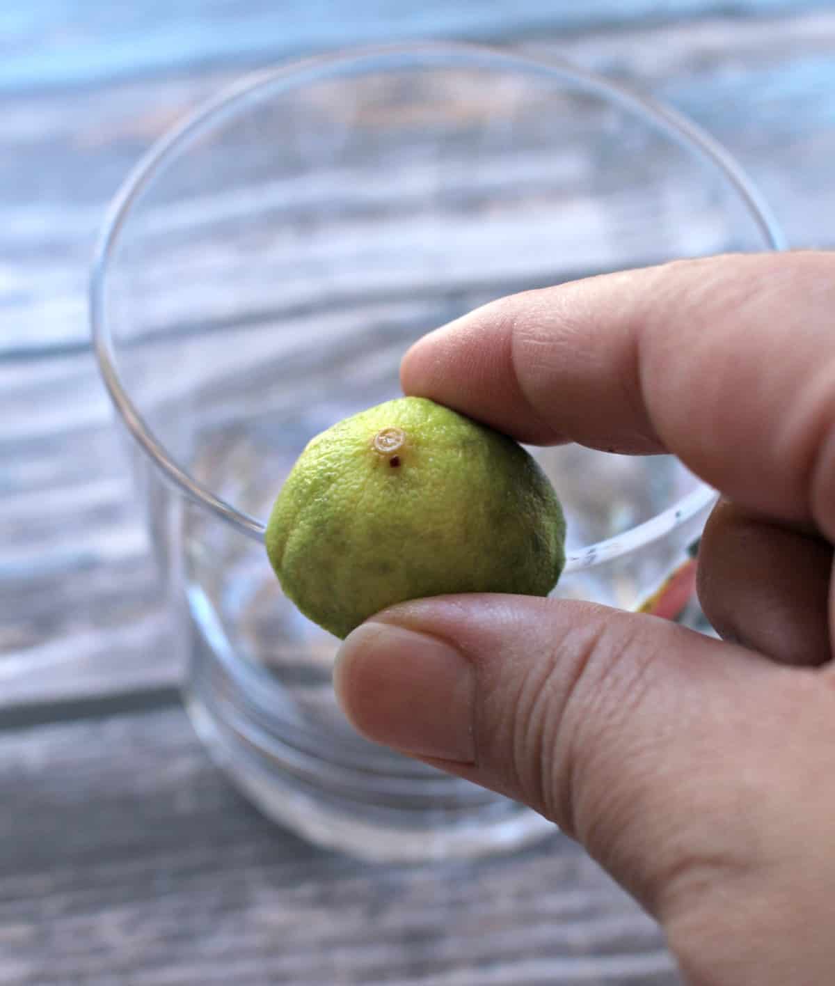 A hand rubbing lime on the rim of a glass.