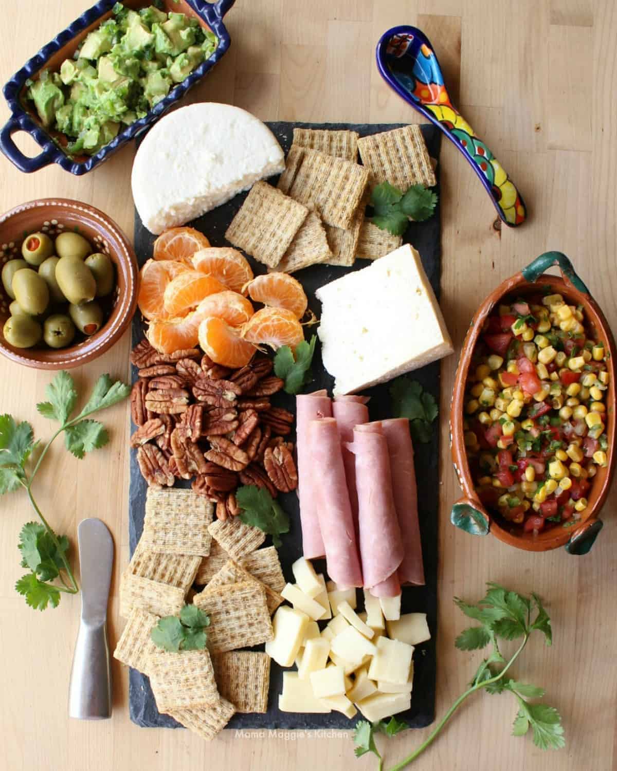Mexican Charcuterie board with guacamole, con salsa, olives, and different kinds of Mexican cheeses.