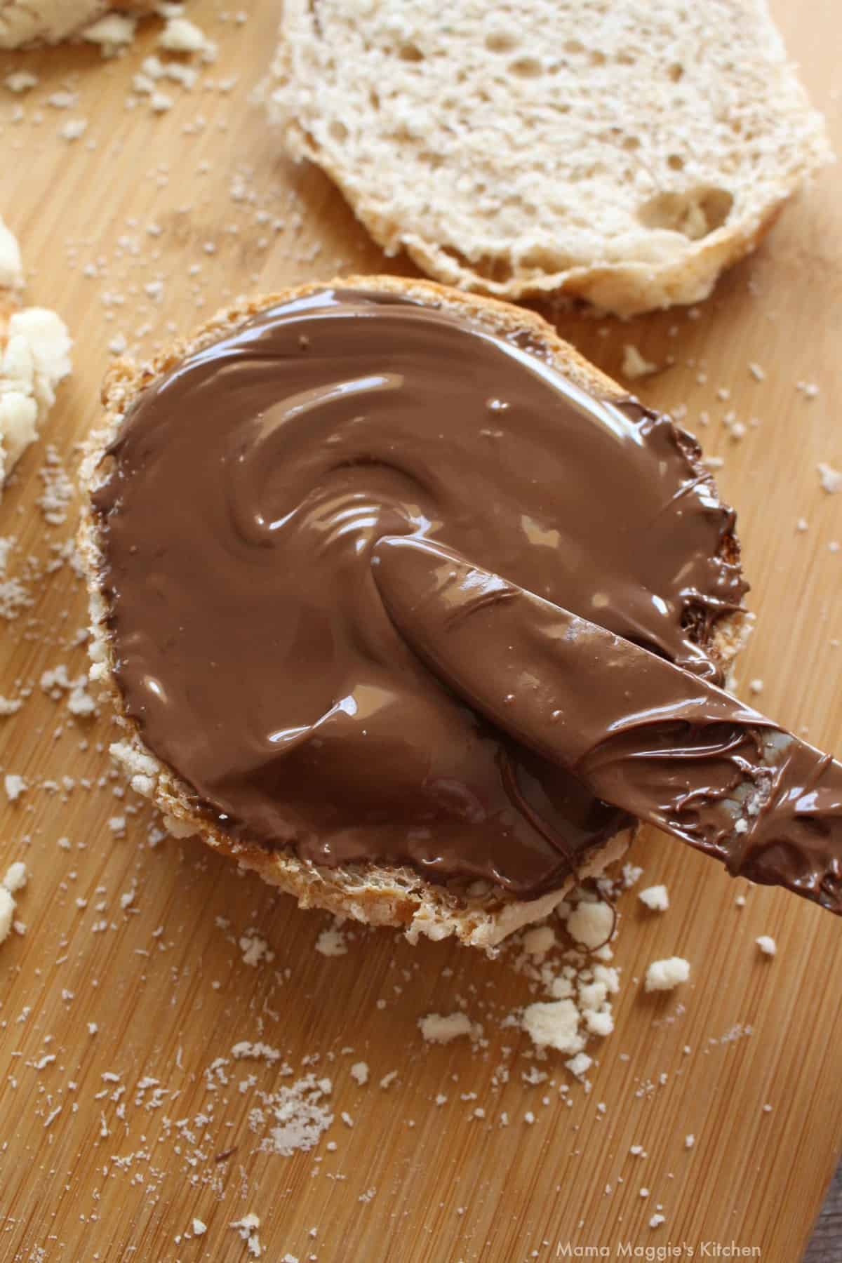 A knife spreading nutella on a concha.