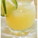 Spiked Agua de Pepino served in a glass and garnished with cucumber and lime slices.