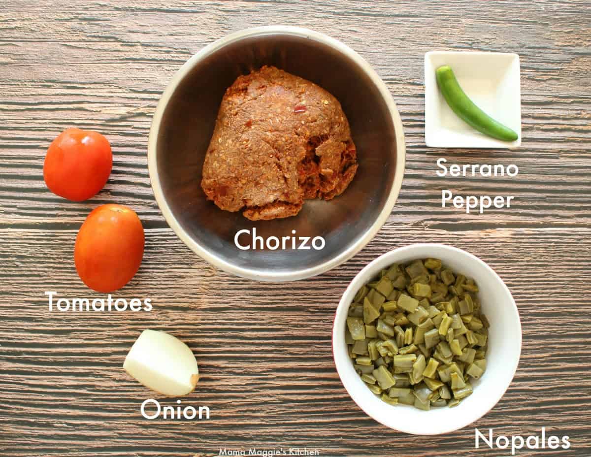 Ingredients for Nopales con Chorizo laid out and labeled on a wooden surface.