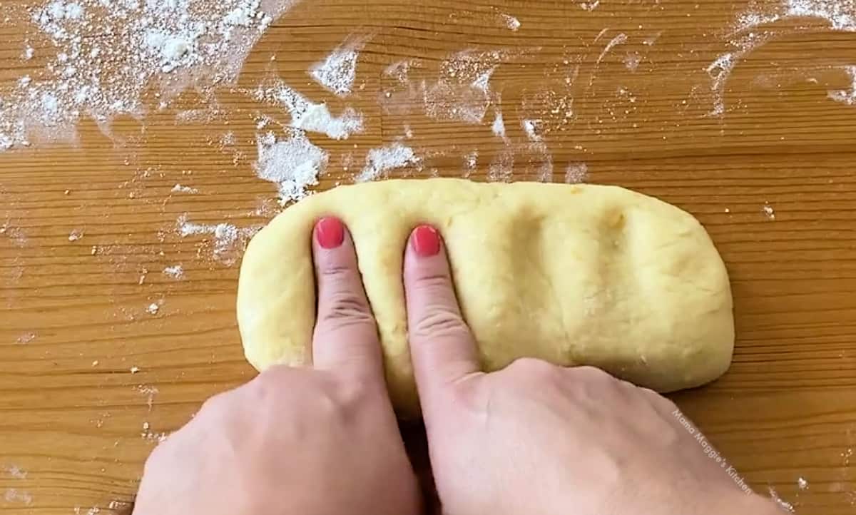Two fingers pressing down on dough.