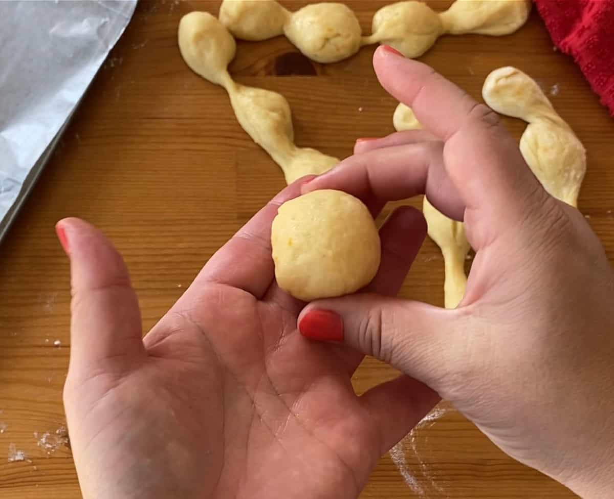 A hand forming a small dough ball.