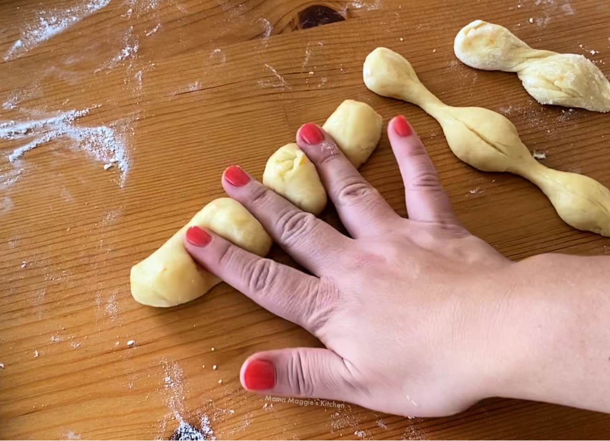 A hand rolling out the dough bones on a floured surface.