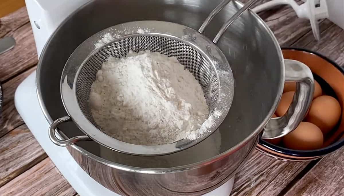 A KitchenAid with a sift over the bowl, sifting flour.