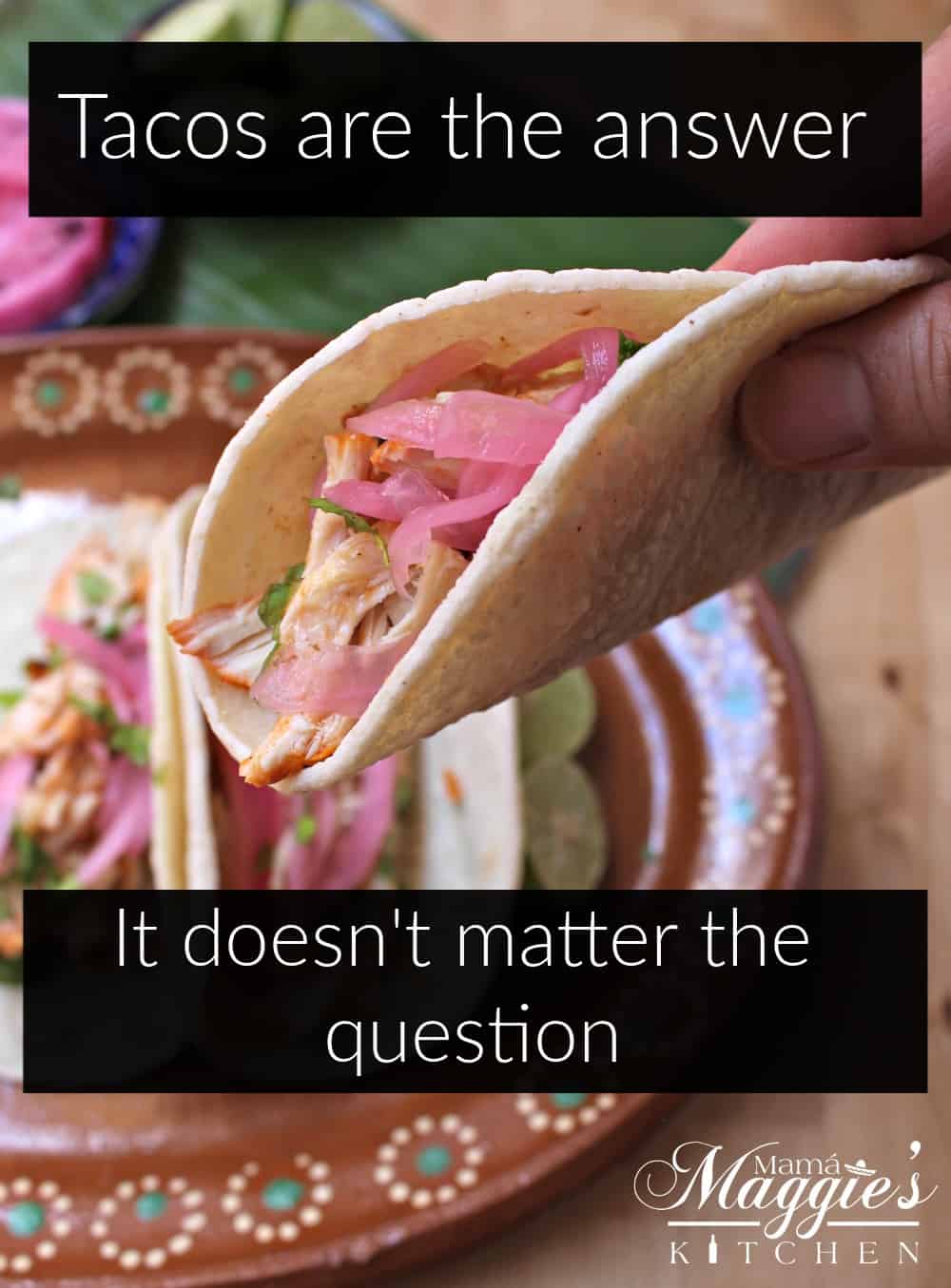 A hand holding a taco topped with pickled red onions.